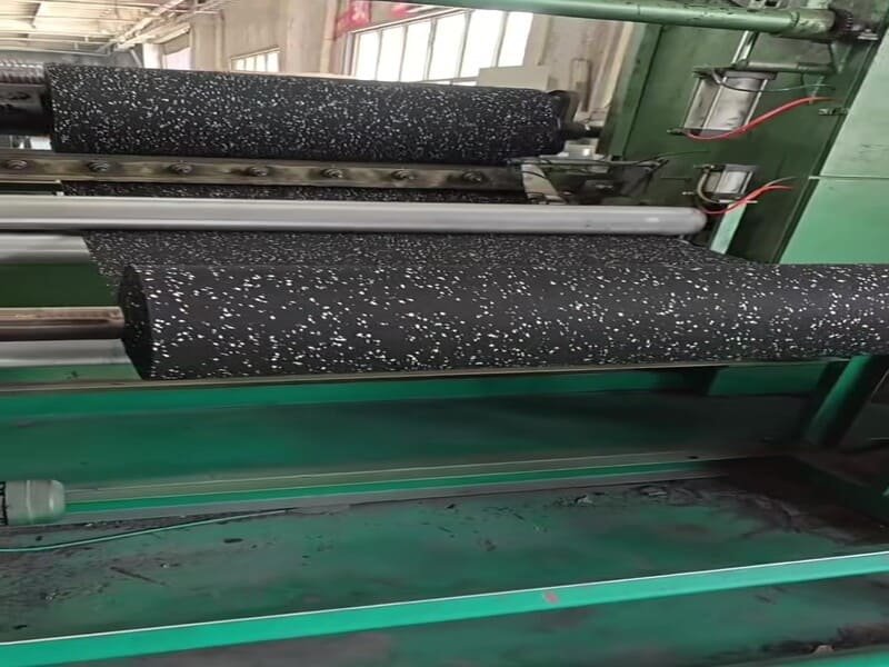 Worker cutting a rubber flooring roll with a straight edge